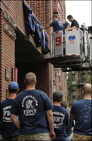 Firefighters from Engine 24, Ladder 5 attach bunting to the facade of their firehouse as other members of their unit look, Aug. 19.