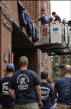 Firefighters from Engine 24, Ladder 5 attach bunting to the facade of their firehouse as other members of their unit look, Aug. 19.