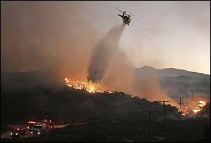 A helicopter drops water on a brush fire in Acton, Calif., Sept. 3.