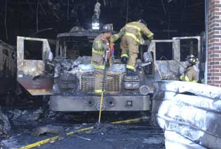 Firefighters work their way down from Engine 733 after clearing smouldering insulation off the roof of the truck Wednesday at Schuylkill Hose Company No. 2, Schuylkill Haven. Flames tore through the company's engine and locker room, destroying two fire engines and a Haz-Mat trailer.