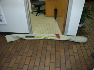 This tarp has been folded in half and rolled to make a dike to prevent water from entering the bathroom. The pick head axe provides some weight to help the dike keep water out.