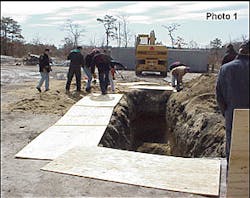 Crews place ground pads around the trench and remove loose soil to the spoil pile on the right. Crews place ground pads around the trench and remove loose soil to the spoil pile on the right.