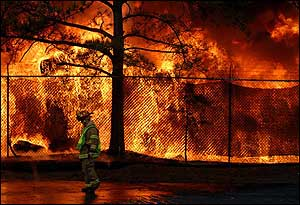 Chuck Waldsmith, a captain with the Fulton County Fire Department, walks the fire line, watching neighboring buildings.