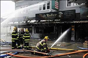 Firefighters train their hoses on a Dough Roller restaurant.