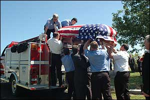 Macon firefighters load the casket of their chief onto the engine on Tuesday.