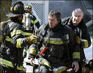 Scorched firefighters exit the front of of a three alarm blaze on Harrison Street in Brookline.
