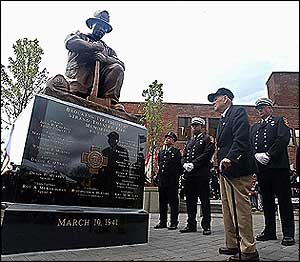 Retired Brockton fire Chief Edward Burrell, 93, views the new monument, topped by his likeness, to the fallen heroes of the Strand Theatre fire.