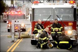 James Velasco, kneeling, and fellow firefighters rest after battling the blaze.