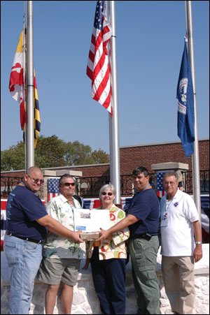 Brandon Thompson's brothers, Jeff, left, and Frank hold a brick from the Sofa Super Store while their parents, Frank Thompson and Diane White, hold an article about the deadly blaze. Retired New Bedford Chief Roger Nadeau assisted them this weekend.