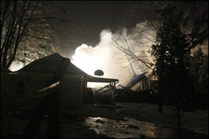Firefighters spray and foam at the scene where a plane crashed into a house and burned in Clarence Center, N.Y.