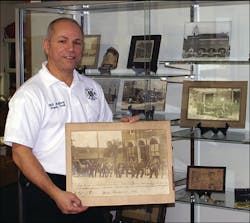 Deputy Chief Mallory stands with an early photo of the department, dated 1891.