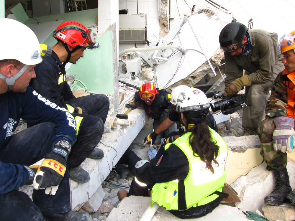 Paramedic Greg Tabeek, left, and Spanish USAR team member Matias Monedo, top left, prepare to swap out with Lt. Beardsley, who's coming out from underneath the hospital.