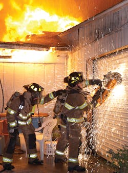 Firefighters Jeremy Bishop, left and David Hill with use a rotary saw to gain access to the fire building.