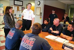 Joanne Turner (standing, left) and Osceola County Fire Rescue Chief Richard Collins (standing right) talk with a crew at one of the Osceola County fire stations.