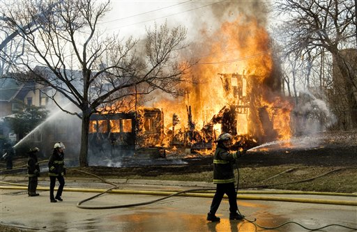 Flint firefighters try to contain a two story vacant structure fire on March 24, the same day the city began laying off a quarter of its firefighters.