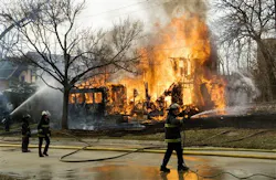 Flint firefighters try to contain a two story vacant structure fire on March 24, the same day the city began laying off a quarter of its firefighters.