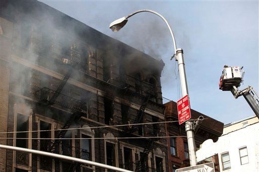 Firefighters in a lift try to get a closer look at a still-smoldering building where a fire started early April 12.