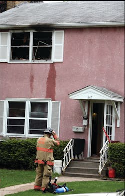 A firefighter removes his gear after exiting the building. The second floor window is what blew out as crews entered the structure. A firefighter removes his gear after exiting the building. The second floor window is what blew out as crews entered the structure.
