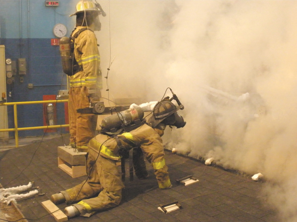 A modern lightweight metal gusset truss roof with a ceiling. This photo depicts significant volume and velocity of smoke during initial portions of the test.