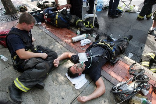 Exhausted firefighters lie on the street while fighting a major fire that engulfed a number of stores in White Plains, N.Y., Wednesday, July 7, 2010.