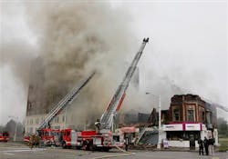 Detroit firefighters battle a burning two-story partially collapsed building with aerial units. Detroit firefighters battle a burning two-story partially collapsed building with aerial units.