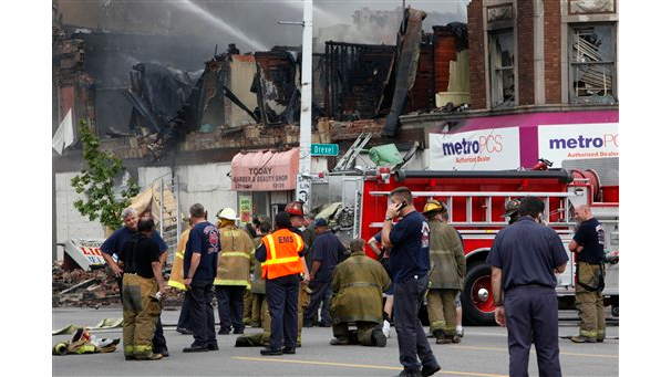 Detroit firefighters stand by as aerial units battle a burning two-story partially collapsed building that injured multiple firefighters.