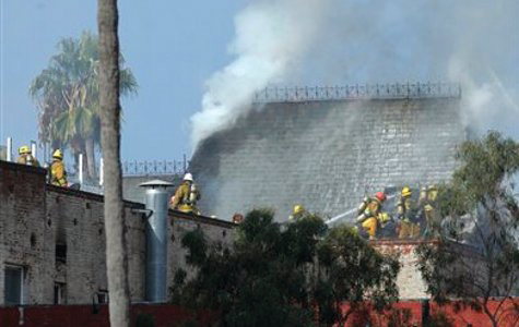 Los Angeles firefighters work to contain a fire that burned through the roof of a six-story apartment building.