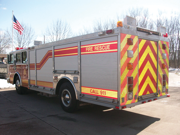 A rear chevron retrofit shows how reflective trim and chevrons enhance the appearance of an unpainted apparatus body.