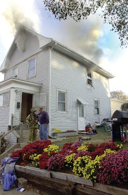 A Logansport firefighter climbs to the roof peak to vent smoke from the attic of a two-story house that caught fire early Wednesday morning.