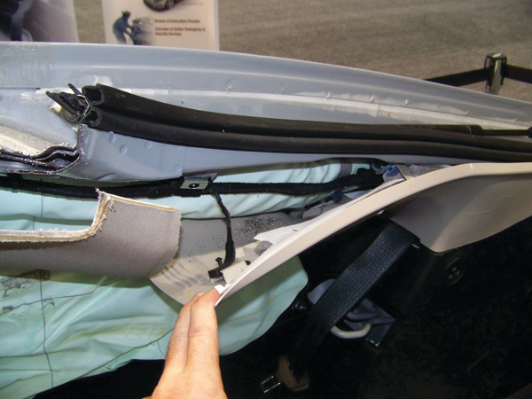 Even with the interior trim piece on the C-pillar peeled away, the steel inflator module is still not visible. The inflator unit is completely wrapped inside nylon airbag material. The exact location of the inflator can be determined by feeling with a hand to confirm exactly where it is mounted prior to cutting the rear C-pillars.