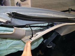 Even with the interior trim piece on the C-pillar peeled away, the steel inflator module is still not visible. The inflator unit is completely wrapped inside nylon airbag material. The exact location of the inflator can be determined by feeling with a hand to confirm exactly where it is mounted prior to cutting the rear C-pillars.
