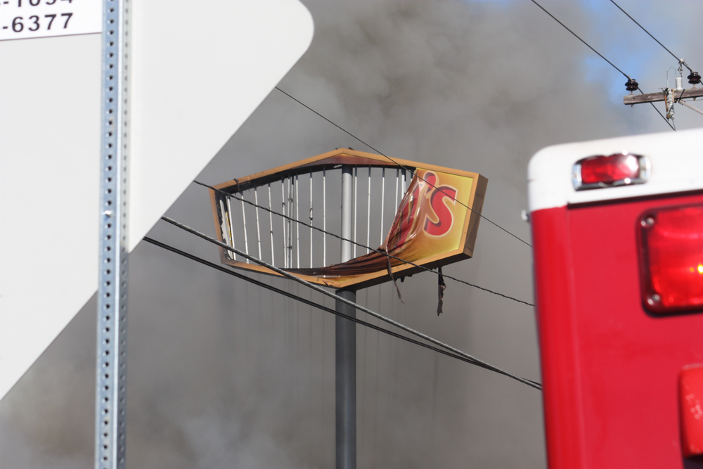 The fire burned-away the 30-foot sign at the road.