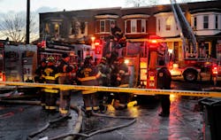 Firefighters investigate the scene outside the rowhome where three adults and three children died in an early morning two-alarm fire.