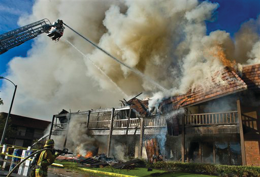 A roof begins to collapse as firefighters pour water on the blaze in Tustin, Calif.