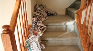 Newspaper is used to create a trailer on the stairs of a dwelling in this training prop. The trailer will move the fire from the first floor to second floor landing.