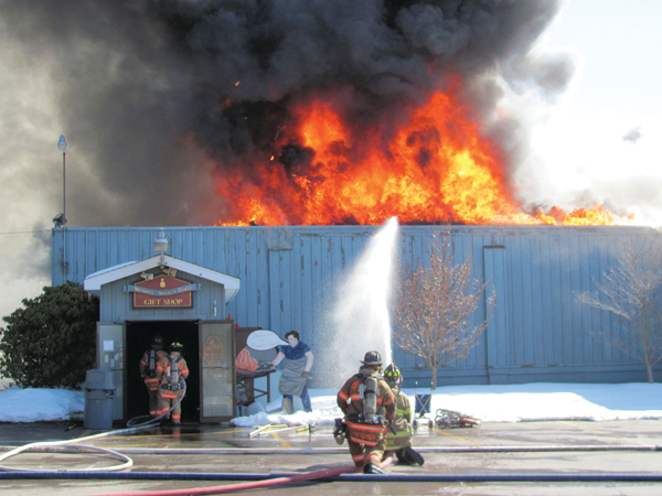 Firefighters enter the showroom to help stop the spread of the fire into the office area.