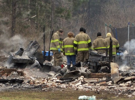 Members of the Beauregard Parish Fire Department look over the scene of an early morning fire that claimed the lives of a mother and her two children.