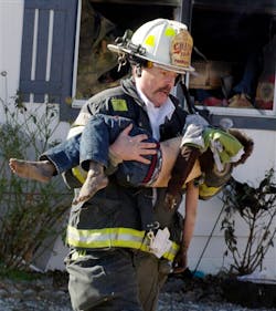 Pahrump fire Chief Scott Lewis carries a fire victim to a waiting ambulance during a mobile home fire.