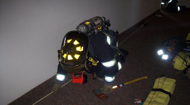 On-duty members practice using search rope techniques in a vacant high-rise building. Note the carrying of two flashlights by this firefighter, one on the coat and one on a sling.