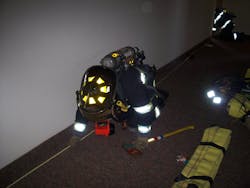 On-duty members practice using search rope techniques in a vacant high-rise building. Note the carrying of two flashlights by this firefighter, one on the coat and one on a sling.