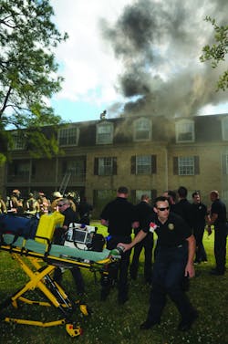 HOUSTON, TX, MARCH 21, 2011 &ndash; Houston Fire Department EMS crews assemble equipment for an EMS staging area near a burning three-story retirement center. The fire was reported shortly before 4 P.M. and escalated to three alarms. The flames appeared confined mainly to an attic space, but the third floor was filled with smoke. All of the estimated 90 residents were soon accounted for outside after many were assisted by firefighters and few requested onsite evaluation by EMS. One firefighter was taken to a hospital for evaluation after complaining of chest pains.