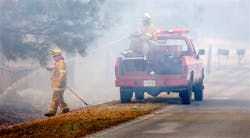 Smoke envelopes firefighters as they work to keep a grass fire from jumping the road in Choctaw, Okla. on March 11.