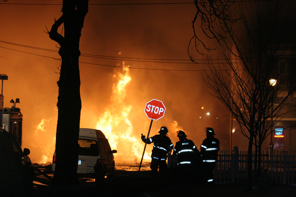 An A Division second-alarm company monitors an unmanned deluge gun covering the D exposure.