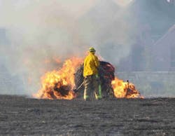 A Lewisville Fire Fighter assesses a burning round bale and waits for a brush truck to help knock it down. A Lewisville Fire Fighter assesses a burning round bale and waits for a brush truck to help knock it down.