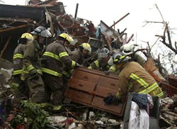 Firefighters from Oklahoma move a dresser while searching for victims in the wreckage of a public housing complex in Joplin.