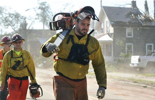 Firefighters from the Massachusetts Bureau of Forrest Fire Control walk down a street filled with damage from the tornado in Springfield earlier this month.