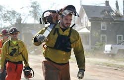 Firefighters from the Massachusetts Bureau of Forrest Fire Control walk down a street filled with damage from the tornado in Springfield earlier this month.