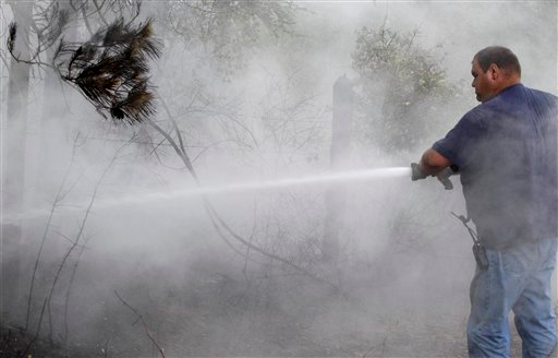 Volunteer firefighter Stephen Kimich sprays an area that had flared back up on June 20 in Stoneham.