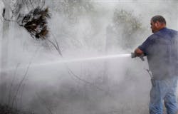 Volunteer firefighter Stephen Kimich sprays an area that had flared back up on June 20 in Stoneham.