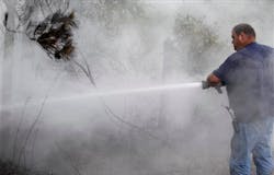 Volunteer firefighter Stephen Kimich sprays an area that had flared back up on June 20 in Stoneham. Volunteer firefighter Stephen Kimich sprays an area that had flared back up on June 20 in Stoneham.